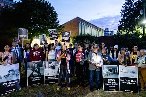 A diverse group of activists at a Tsuru for Solidarity town hall hold signs protesting U.S. immigration detention, referencing Japanese American incarceration during WWII.