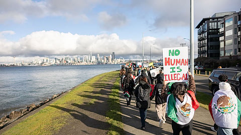 Activists march along Alki Beach to protest the U.S. Immigration and Customs Enforcement (ICE) and the Trump administration's immigration policies on Feb. 2, 2025. One holds a sign that reads "No Human Is Illegal."