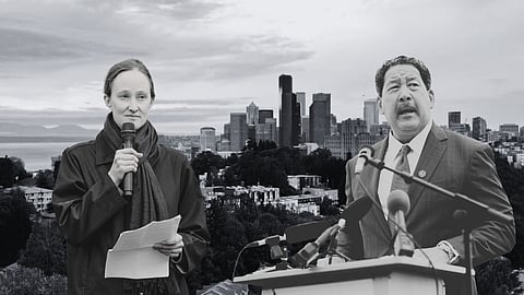 Black-and-white photo of two people speaking at podiums with microphones, set against the Seattle skyline; the woman holds notes and a microphone, while the man gestures while speaking.