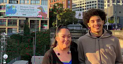 Abigail Echo-Hawk and G'Centae Rodriguez stand in front of a billboard on Yesler Way for "Magical Millie’s Courageous Journey."