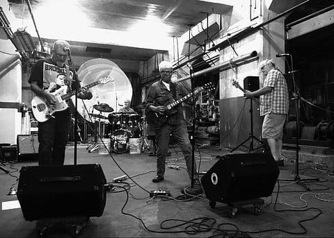 Seattle band Student Nurse playing last year's Possibilities Expo; the three band members are all playing instruments amid speakers, cords, and lights at the Georgetown Steam Plant.