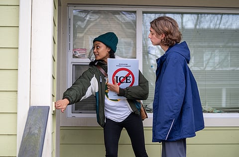 Two volunteers, Maria and Ira, knock on a door in Seattle’s New Holly neighborhood, holding an anti-ICE.