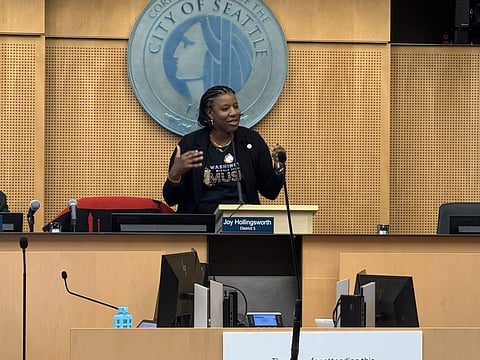 Seattle City Councilmember Joy Hollingsworth speaks at a podium during a City Council meeting, gesturing as she addresses the chamber after being selected as council president, with the City of Seattle seal displayed behind her.