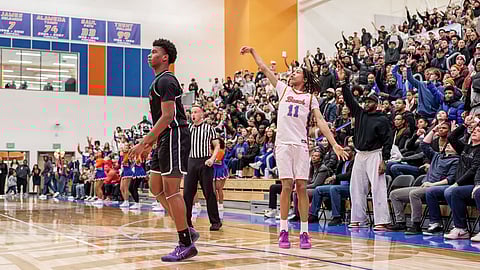 J.J. Crawford of Rainier Beach holds his shooting follow-through as the crowd waves goodbye after he hits a late three-pointer against Eastside Catholic in a packed high school gym.