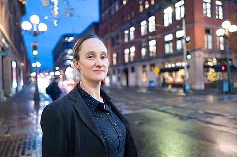 Katie Wilson stands against the backdrop of lights and buildings in Pioneer Square.