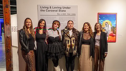 Six artists—Alison Bremner, Cassandra Butler, Chelsea Moore, Stef Marchand, Martina Kartman, and Susan Hollman—stand together at the “Living and Loving Under the Carceral State” exhibit at King Street Station Gallery.