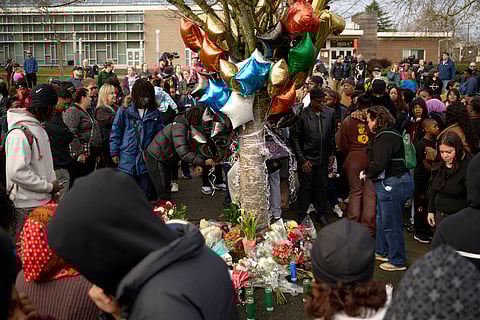 A crowd places candles, flowers and balloons at a vigil near a bus stop in Rainier Beach