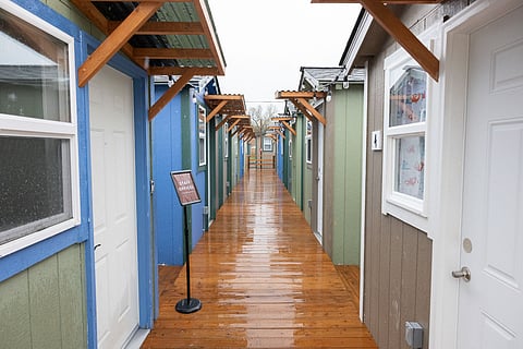 A row of small shelter units stands along a walkway at Tukwila’s new tiny house village.