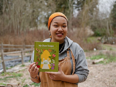 Chef Nurhaliza Mohamath poses with a hard copy of her first cookbook, My Cham
Tongue, at Rainier Beach Urban Farm and Wetlands in Seattle on March 15, 2026.