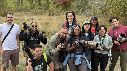 Participants in a BIPOC Bird Photography Walk stand together with cameras at Magnuson Park.