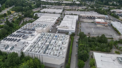 A data center occupies the foreground of a Tukwila industrial park with Seattle visible in the distance.