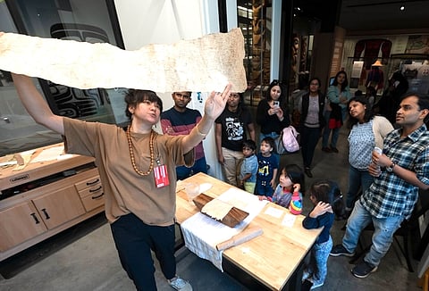 Malia Peoples holds up thin sheet of cloth.