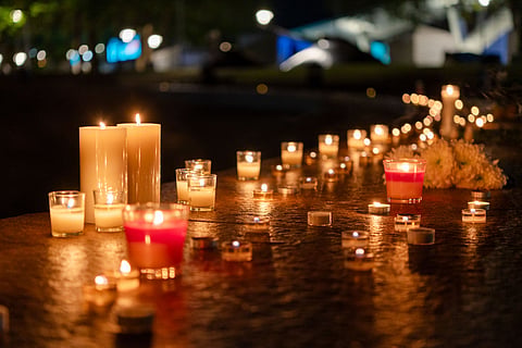 Candles and flowers along the fountain at night.