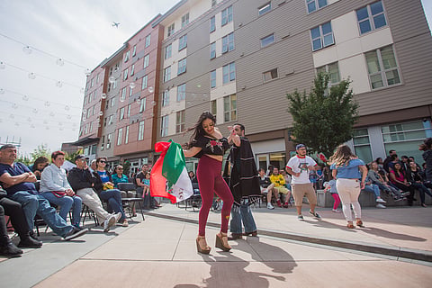 A woman holding a Mexican flag and her partner dance to music, during Centilia Cultural Center's Cinco de Mayo celebration at Plaza Roberto Maestas in Seattle, Washington, on May 5, 2018. (Photo: Carolyn Bick)