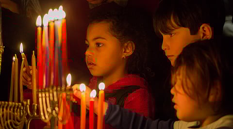 Djanae Parramore, center, lights a menorah, during Kadima Reconstructionist's Chanukah party at the 2100 Building in Seattle, Washington, on Dec. 8, 2018. (Photo: Carolyn Bick)