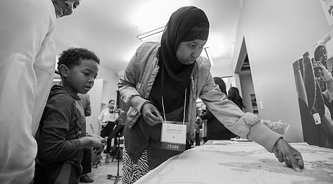 ReWa staffer Sagal Osman Danan, center, places a butterfly sticker on a map meant to trace event attendees' origins, during a private event to view the new space at ReWa's main campus, on Nov. 8, 2018. (Photo: Carolyn Bick)