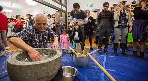 Stephen Ou, back center, and daughters Raina, center, and Sunya, back left, watch Takumi Yoshinaga, front left, clean the stone mochi pounding bowl, during the annual mochitsuki at the Japanese Cultural Center in Seattle, Washington, on Jan. 27, 2019. (Photo: Carolyn Bick)