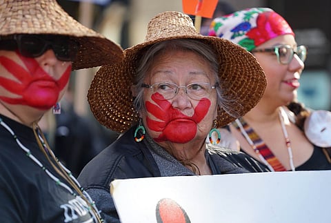 Laverne Wise, center, and her daughter Jessica Dominy, left, wear the symbol of the red hand on their faces to acknowledge missing and murdered Indigenous women and girls, during a rally celebrating Indigenous Peoples' Day at Westlake Park in Seattle, Washington, on Oct. 14, 2019. (Photo: Susan Fried)
