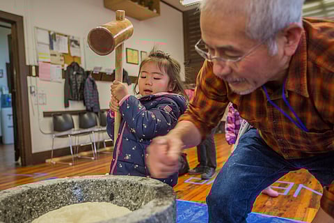 A young festival attendee pounds mochi, as Takumi Yoshinaga, right, kneads the dough in between strikes, during the Japanese Cultural and Community Center of Washington's annual mochitsuki event at its headquarters in Seattle, Washington, on Jan. 12, 2020. (Photo: Carolyn Bick)