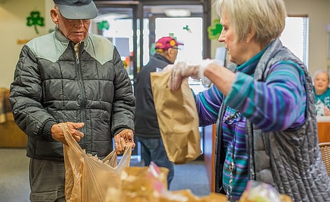 Southeast Seattle Senior Center thrift shop lead Linda Lewis, right, gives center patron Bill, left, another lunchbag, at the Southeast Seattle Senior Center in Seattle, Washington, on March 16, 2020. (Photo: Carolyn Bick)