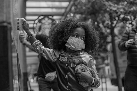 Adia cleans a wall, while holding a stuffed animal, in downtown Seattle, Washington, on May 31, 2020. (Photo: Carolyn Bick)