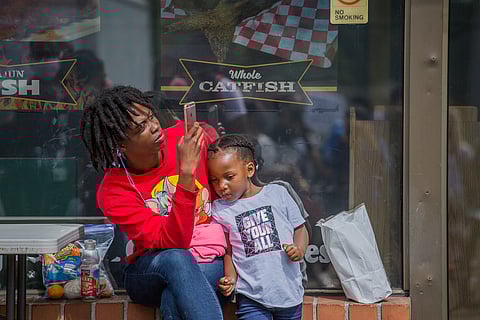 A woman and a young child listen to a speaker, during the Heal the Hood rally in the Skyway neighborhood of Seattle, Washington, on June 28, 2020 (Photo: Carolyn Bick)