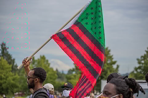 A young man carries a flag, as he marches, during the Juneteenth celebration at Jimi Hendrix Park in Seattle, Washington, on June 19, 2020. (Photo: Carolyn Bick)