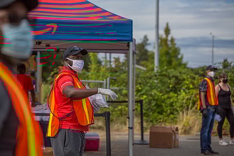 Workers direct drivers at a drive-through mask giveaway at the Rainier Beach Community Center in Seattle, Washington, on Aug. 20, 2020. (Photo: Carolyn Bick)