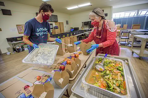 Finn West, left, and Linda Lewis pack hot lunches for seniors at the Southeast Seattle Senior Center in Seattle, Washington, on Aug. 13, 2020. (Photo: Carolyn Bick)