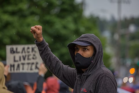 A person holds up a fist in solidarity with marchers, during the March of Silence down 23rd Ave. South, Seattle, Washington, on June 12, 2020. (Photo: Carolyn Bick)
