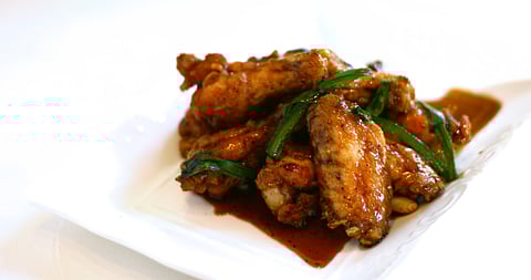 A plate of Phnom Penh Noodle House's signature Phnom Penh Chicken Wings sauteed with jalapeos and green onions in a sweet black pepper garlic sauce. (Photo: Phnom Penh Noodle House)