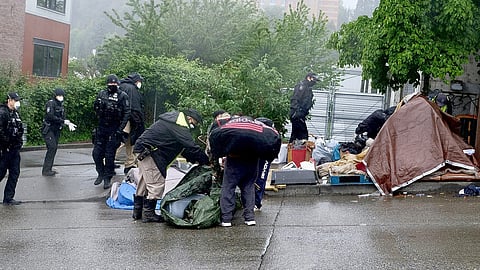 People gather their belongings during a May 20, 2020 sweep of an encampment in the Chinatown-International District. (Photo: Erica C. Barnett)
