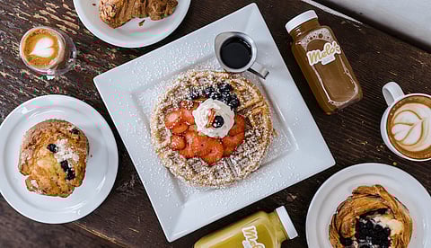 A plate of fruit and cream Belgian waffles, bottles of Melo Juice, pastries, and coffee from Melo Cafe in the Central District. (Photo: Melo Cafe)
