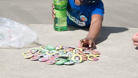 A newly vaccinated youth reaches for a souvenir button at a Vax to the Max event at the ShoWare Events Center in Kent. Eight different local King County artists have created a vaccine-related image that has been turned into a button as a souvenir for those who have just been vaccinated. (Photo: Erin Murphy)