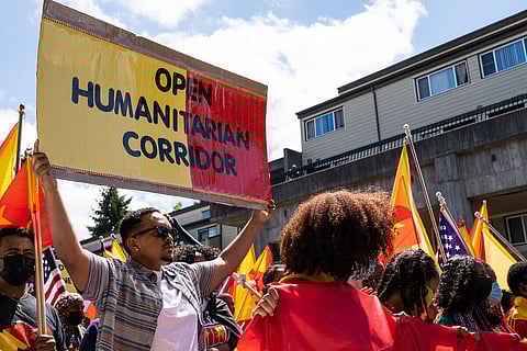 A protestor holds a sign behind local Tegaru youth that led the march down East Yesler Way. (Photo: Ronnie Estoque)