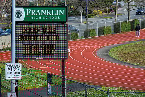 Following school closures in March 2020, a community member walks at the track outside of Franklin High School in South Seattle. (Photo: Sharon Ho Chang)