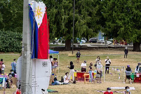 The flag of the Philippines hangs over Othello Park as the crowd listens to a speaker. (Photo: Ronnie Estoque)