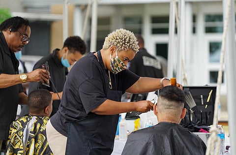 Jocelyn Mayhle from Frank's Barbershop does a free haircut during FAST's annual "Barbershop Cut, Chat, Chew, and Play" event on the Rainier Beach Community Center plaza on July 31, 2021. (Photo: Susan Fried)