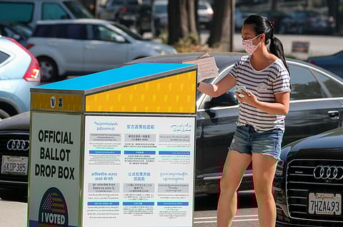 A woman wearing a face mask drops her ballot into an official ballot drop box Tuesday, Oct. 20, 2020, in Burbank, CA. Photo is attributed to Ringo Chiu (under a Shutterstock license).
