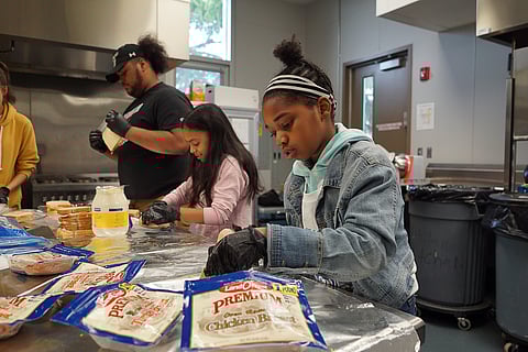 A young volunteer prepares turkey sandwiches to give away to families at Othello Village during the 2018 Turkey Bowl Week of Service. (Photo: Susan Fried)