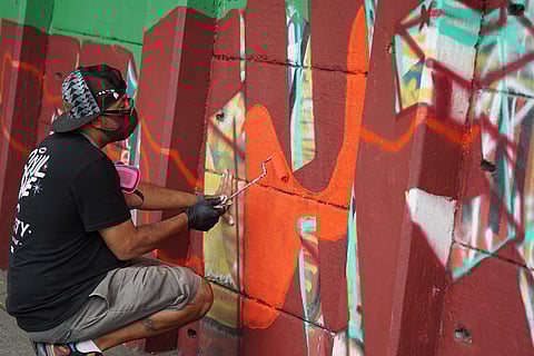 Artist Sam Sneke works on the "Power to the People" mural, located at the intersection of Rainier Avenue South and South Genesee Street, in August of 2020. (Photo: Susan Fried)