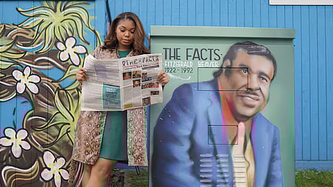 Chardonnay Beaver poses beside a power box that has been painted with a portrait of Fitzgerald Beaver, her grandfather. The power box was painted by local Seattle artist Desmond Hansen.