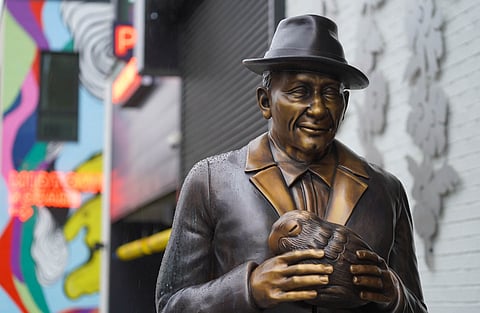 The neon Midtown Square entrance sign gleams from behind the sculpture of Dr. James W. Washington Jr. (Photo: Susan Fried)