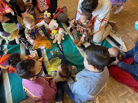 A Native Newborns+ baby welcoming ceremony. Seated, opposite: Andre Fry (Algonquin Anishinaabeg), Montana (Black/Chata), Jack (Nimiipuu) and Edward Krigsman. Seated, below: Orion, Xander, and Caius Love-Thurman (Sac and Fox, Cherokee). Far right: Khalako Lloyd (Mandan & Hidatsa). (Photo: Socia Love (Cherokee))