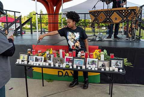 Amia, 14, lights candles on a shrine at Jimi Hendrix Park on May 21 to honor the 10 victims of a white supremacist murderer in Buffalo, New York. (Photo: Susan Fried)