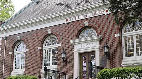 A person studies on the steps of a branch of The Seattle Public Library