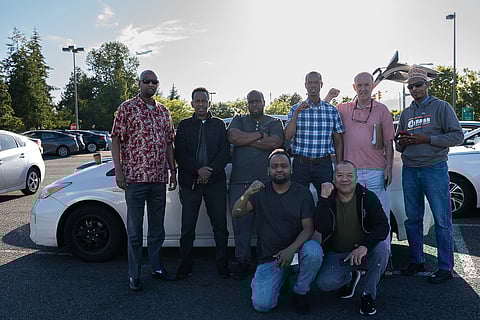 Local rideshare drivers represented by the Drivers Union stand together at a nondescript parking lot located just south of the Tukwila International Boulevard light rail station on Pacific Highway. (Photo: Ronnie Estoque)