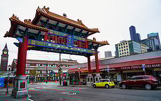 The Historic Chinatown Gate looming over a city street with businesses and a train station in the background.