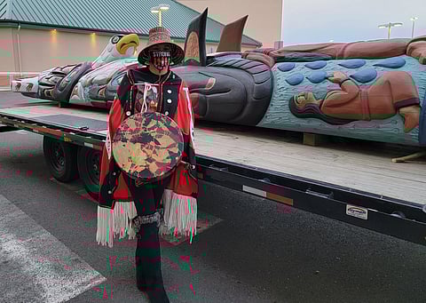 April Obi Boling poses for a photo while holding a Native American drum, standing beside a totem pole. (Photo courtesy of April Obi Boling)