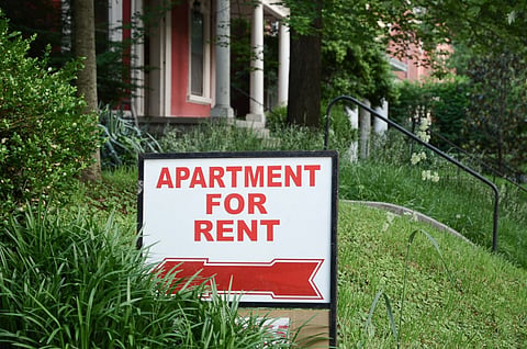 Photo depicting an apartment-for-rent sign displayed on a residential street.